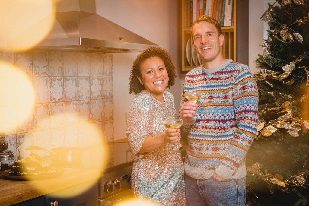 Founders of Brownie and the Bean, Charlotte and Luke Giddings, standing in their kitchen smiling at the camera.