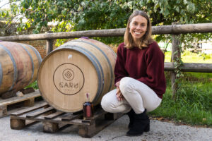 Emily Richards, founder of Caru Spirts, crouching next to a barrel